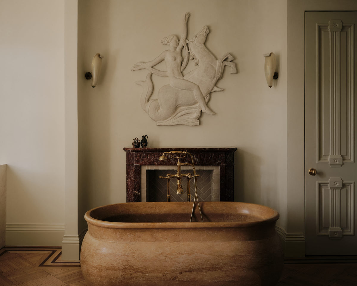 A stone bath beneath a sculptural plaster relief