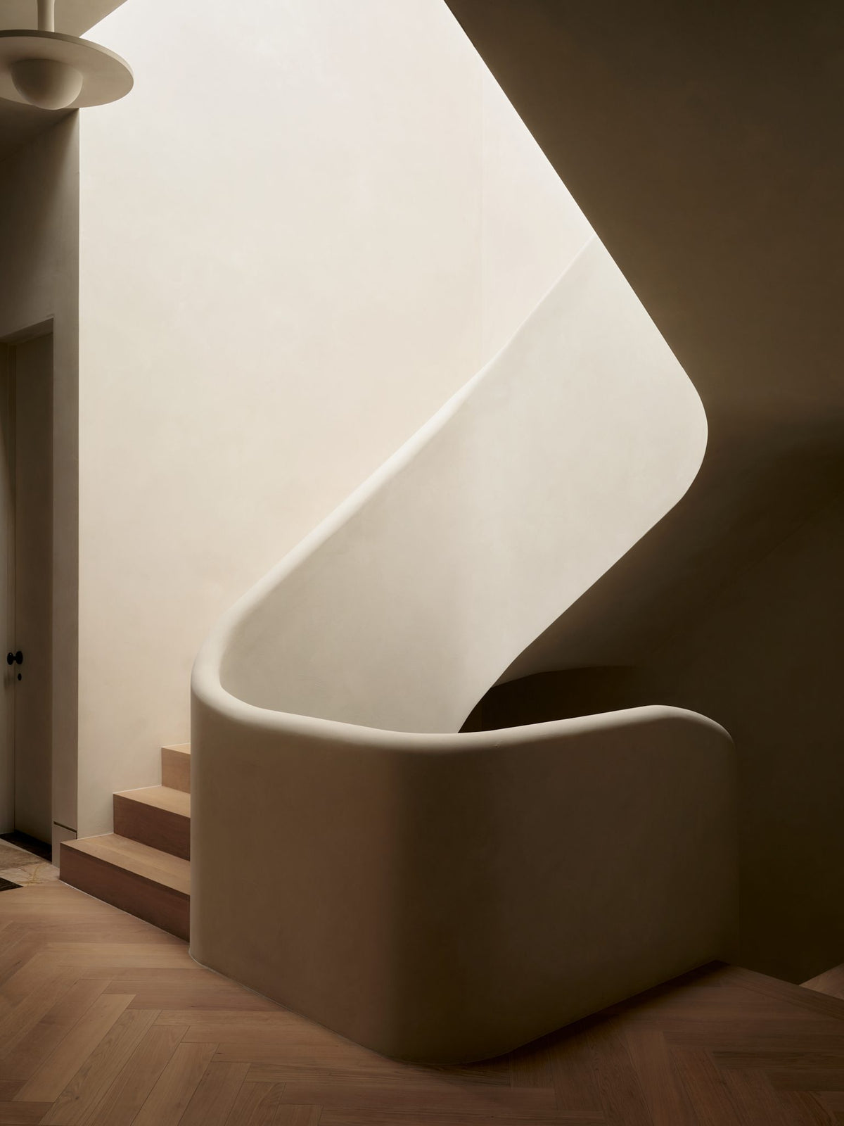 A curving plaster staircase washed in daylight
