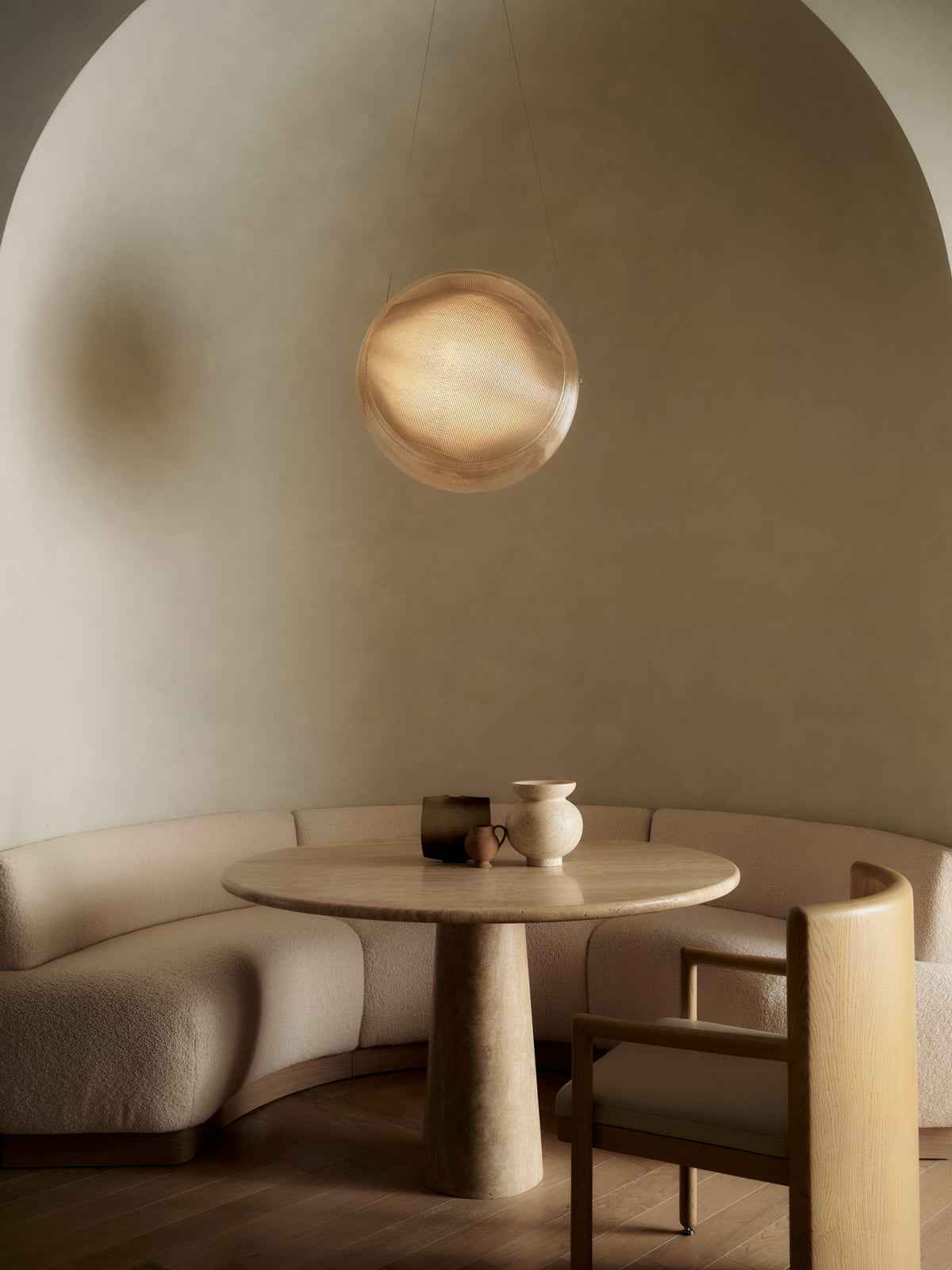 Arched breakfast nook with a round pedestal table, built-in banquette and glowing sculptural sconce