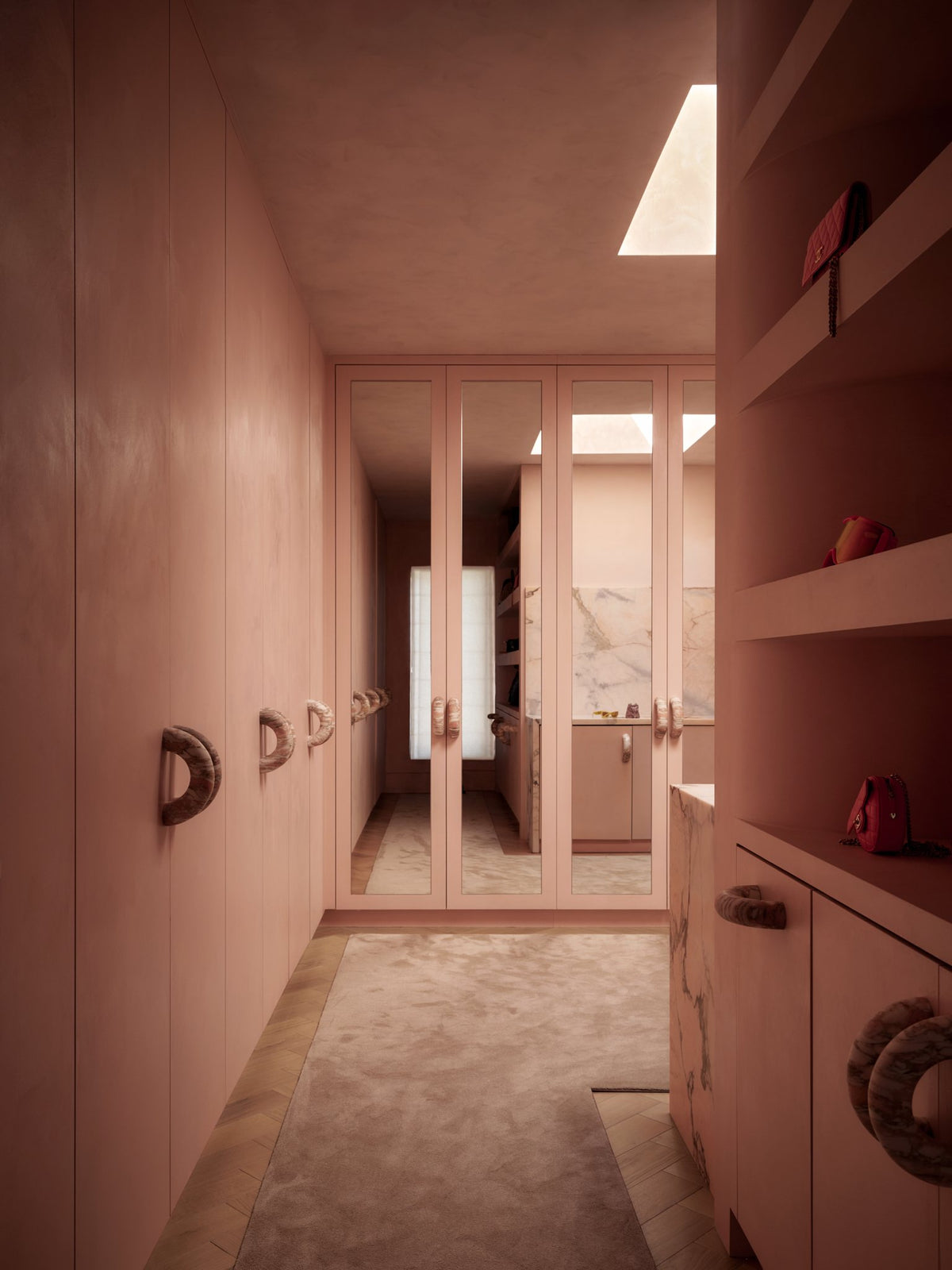 Blush pink hallway with built-in millwork leading to a bright arched doorway