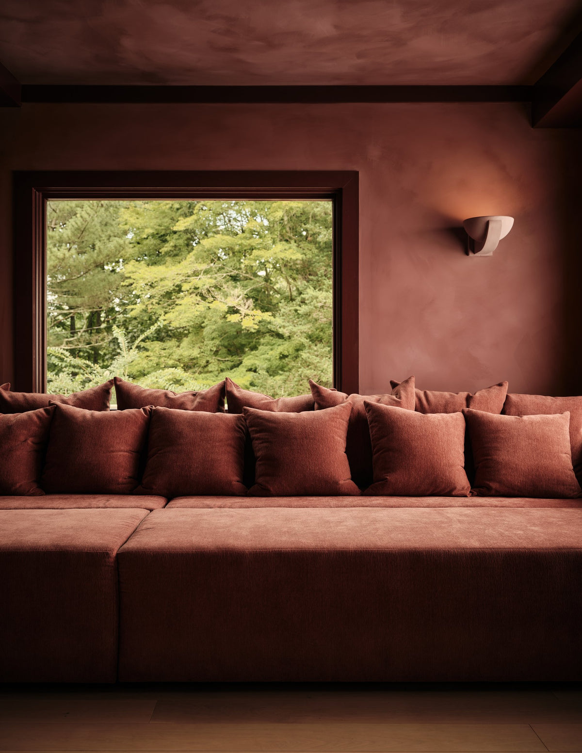 Brendan Plaster Sconce in a red sitting room with a deep window seat and terracotta cushions