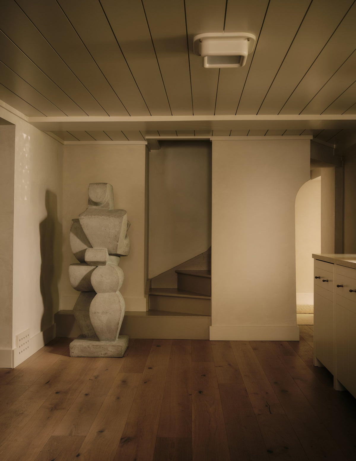 Marshmallow Flush Mount Ceiling Light on a white plank ceiling in an entry hall with a stone sculpture
