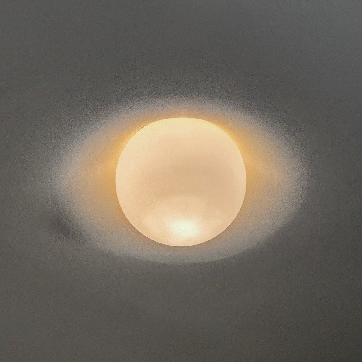 Tommy Plaster Flushmount switched on, glowing frosted globe in a plaster ceiling