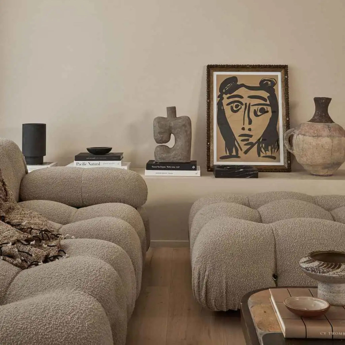 Living room styled with a curved bouclé sofa, vintage portrait and ceramic vessels