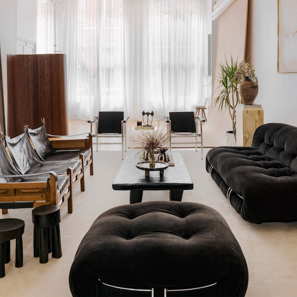 Sunlit room styled with low black bouclé seating and a sculptural floor lamp