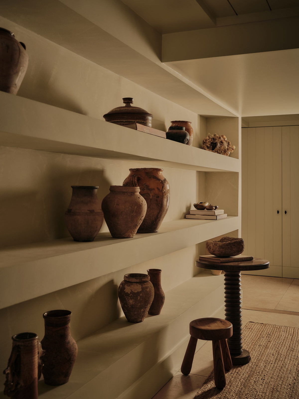Vintage earthenware vessels on built-in plaster shelves