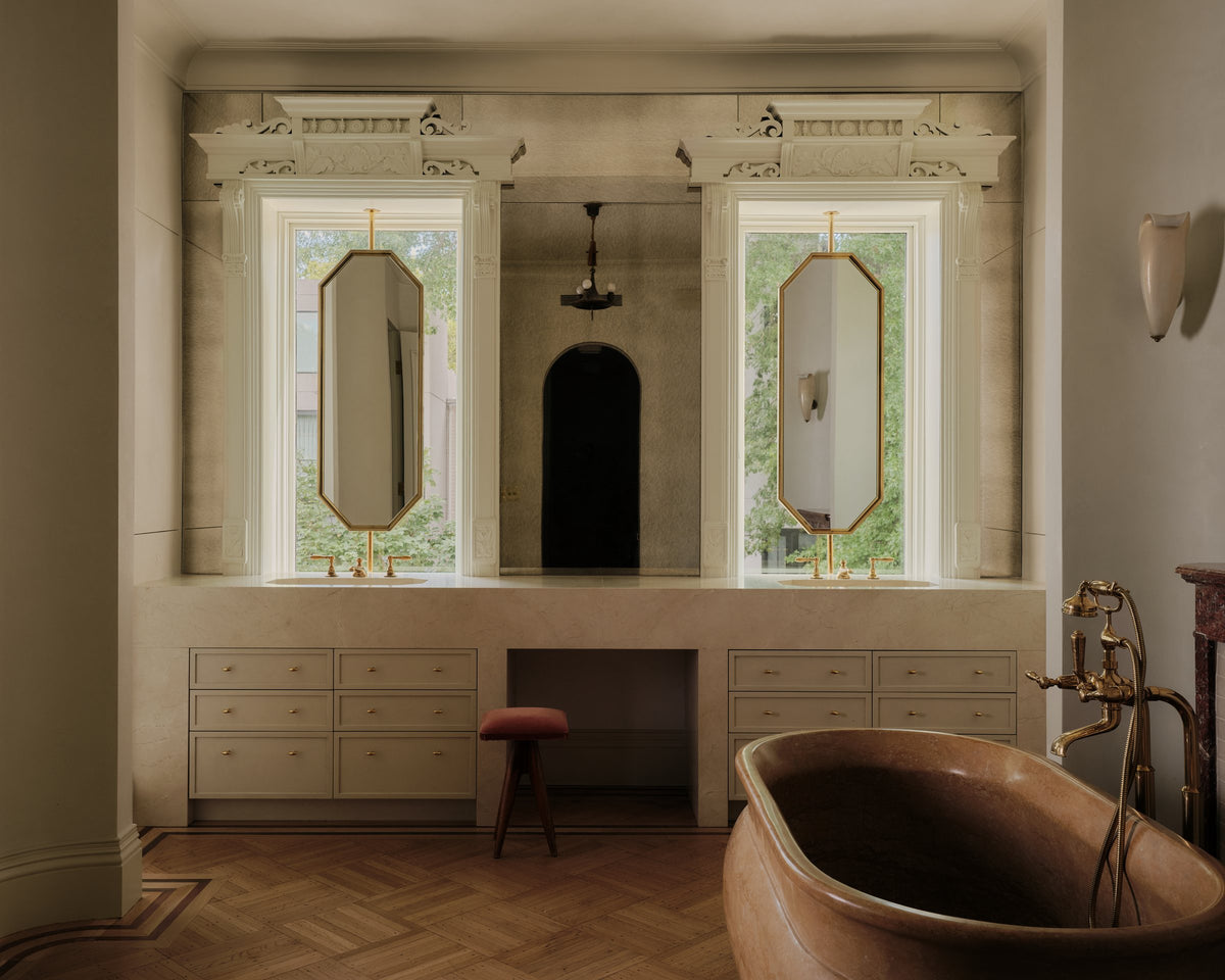 Bathroom with a carved wood tub, twin arched mirrors and a long built-in vanity