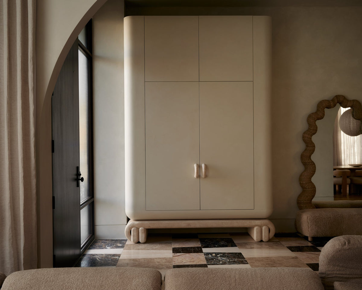 Living room with a plaster archway, built-in cream armoire, scalloped mirror and low sofa