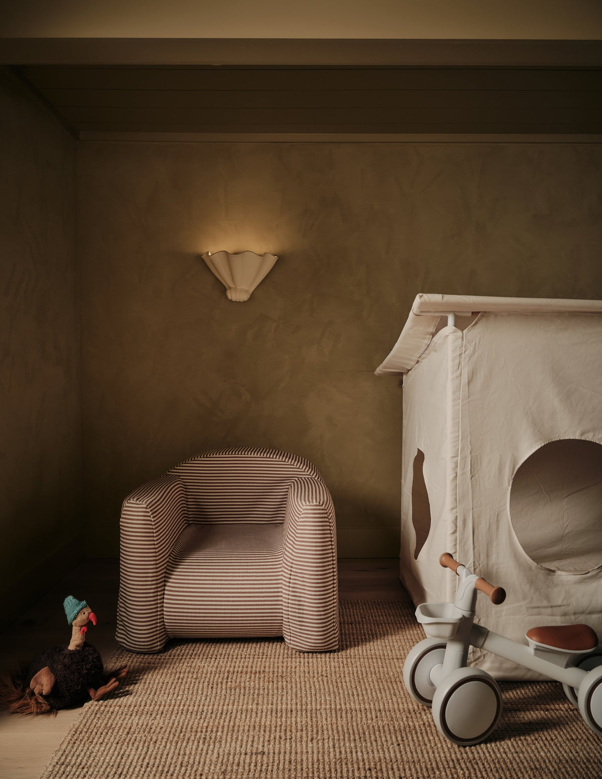 Husk Plaster Sconce glowing on a nursery wall above a bouclé armchair and white crib