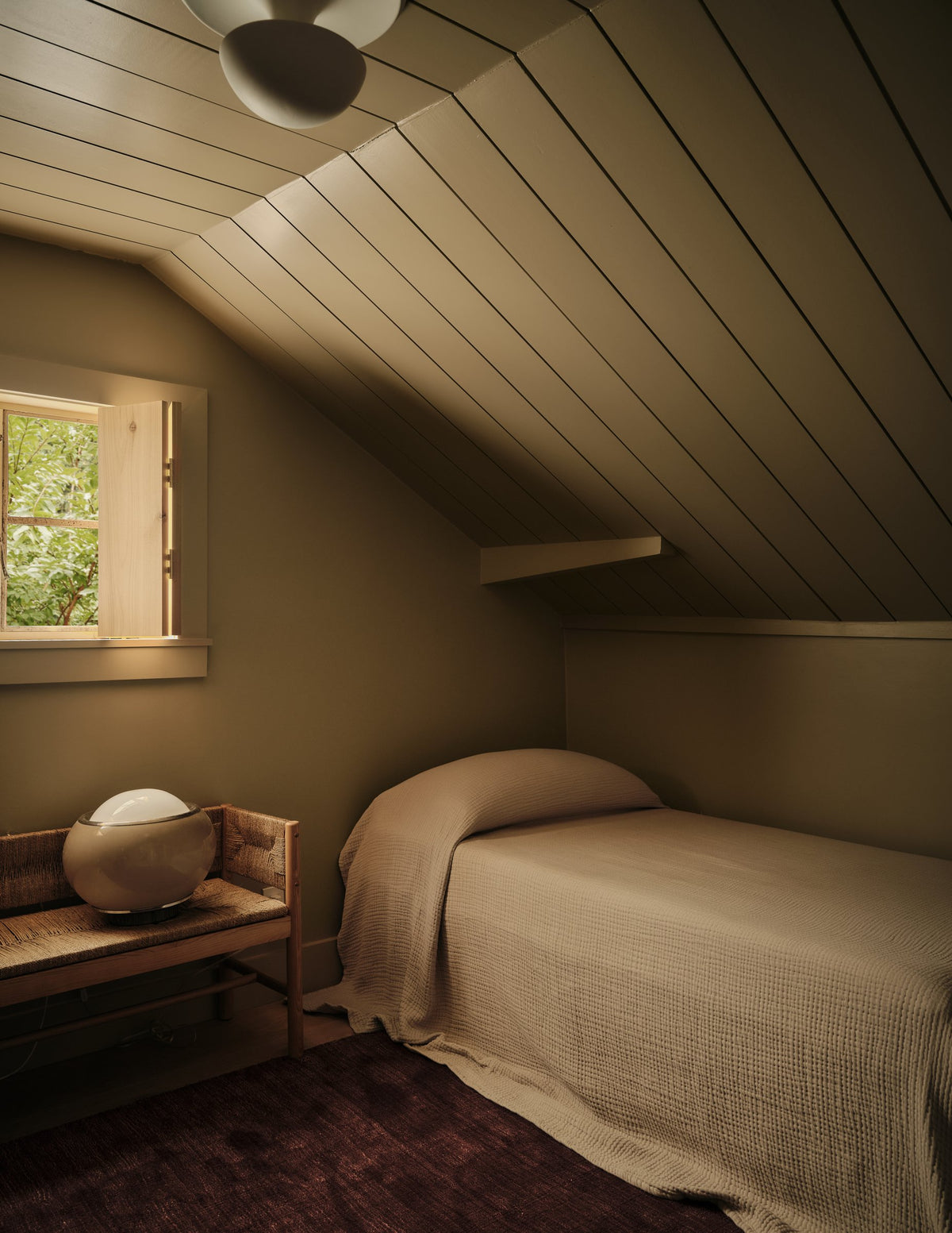 Montana Plaster Ceiling Light on a sloped plank ceiling in an attic bedroom